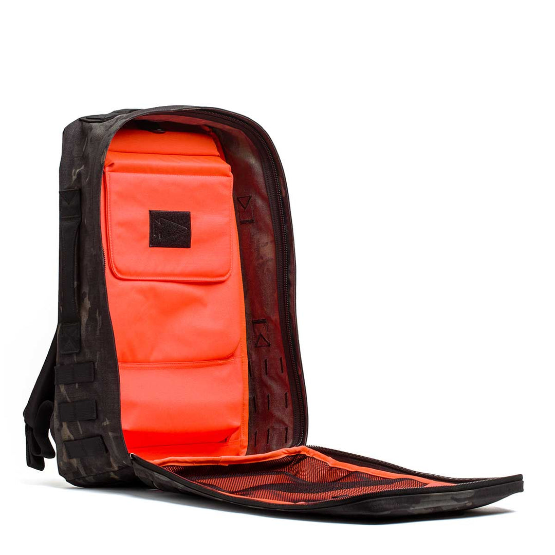 The GORUCK Rucker 4.0 backpack in black with a bright orange interior is shown fully unzipped, revealing inside compartments—ideal for rucking or carrying Ruck Plates.