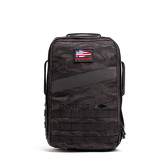 The Rucker 5.0 is a black tactical rucksack featuring an American flag patch, front MOLLE webbing, and built-in lumbar support—ideal for rucking or daily use, shown upright against a white background.