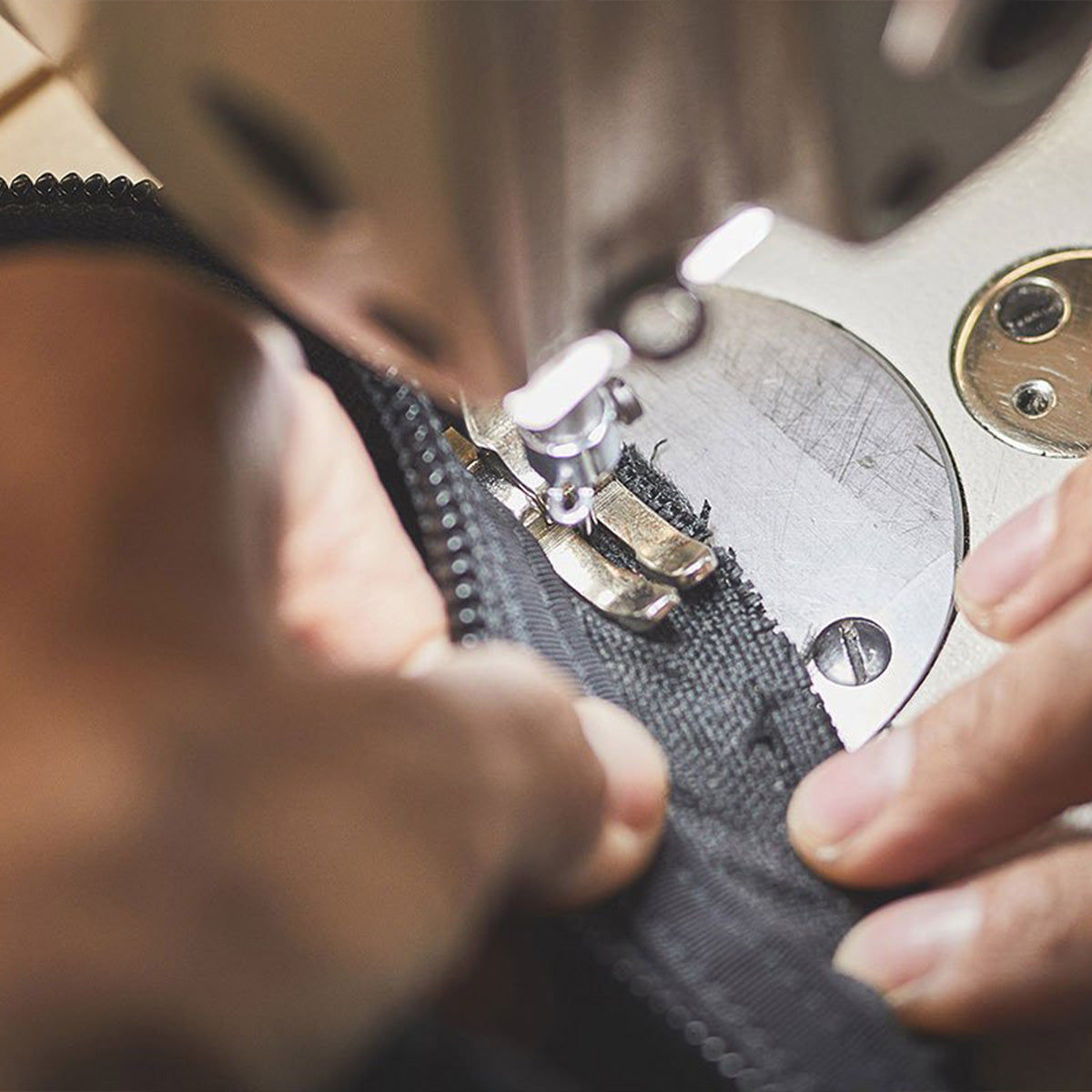Close-up of hands sewing black fabric with a sewing machine.