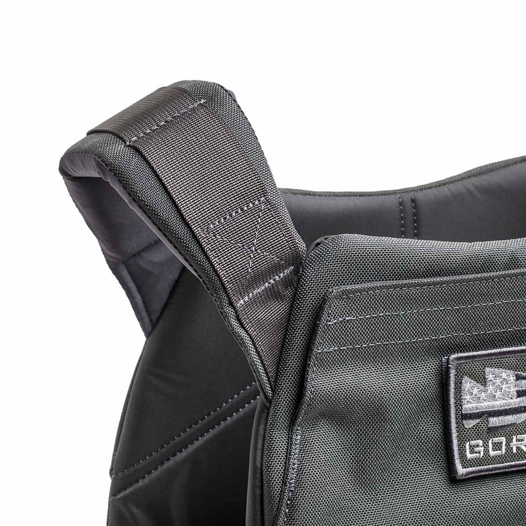 Close-up of the Rucking Weight Vest's black shoulder strap, showcasing detailed stitching and a front patch—perfect for rucking with Curved Ruck Plates.