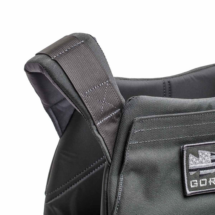 Close-up of the Rucking Weight Vest's black shoulder strap, showcasing detailed stitching and a front patch—perfect for rucking with Curved Ruck Plates.