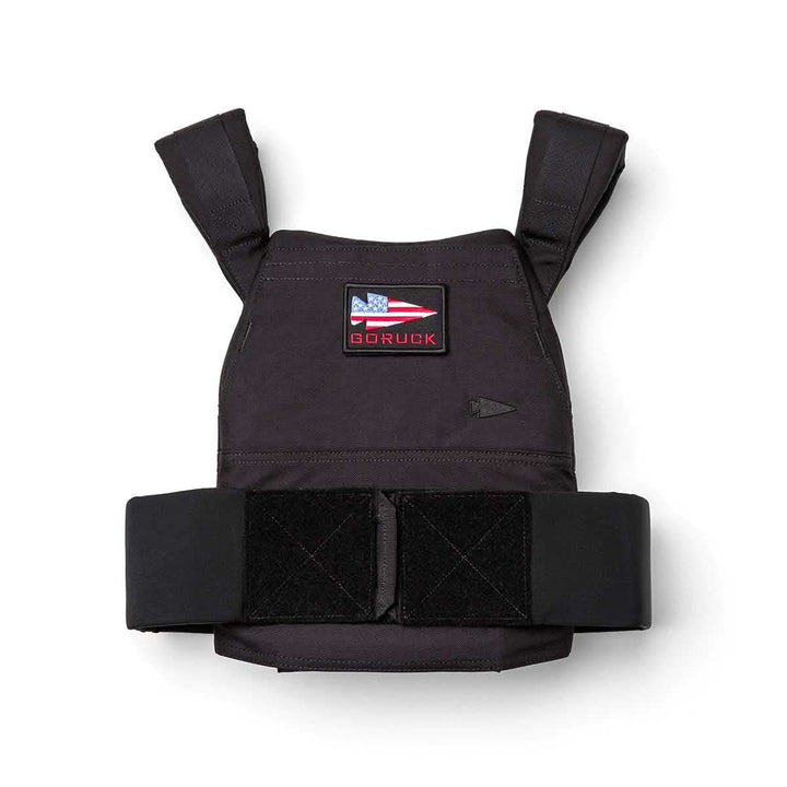 The Rucking Weight Vest features a black design with shoulder straps, Velcro bands, and an American flag "GORUCK" patch. It’s compatible with Curved Ruck Plates for improved comfort and performance during rucking activities.