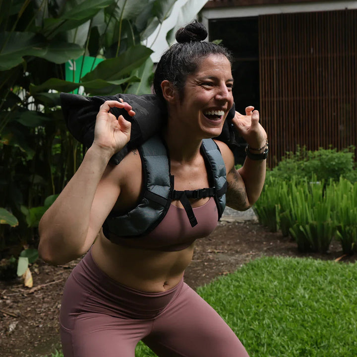 Woman rucking outdoors with GORUCK backpack, smiling during fitness training
