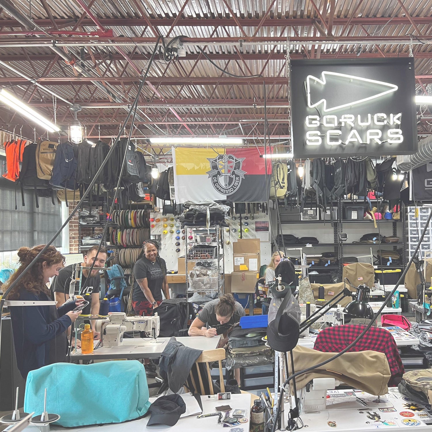 People working in a busy workshop with sewing machines under a 