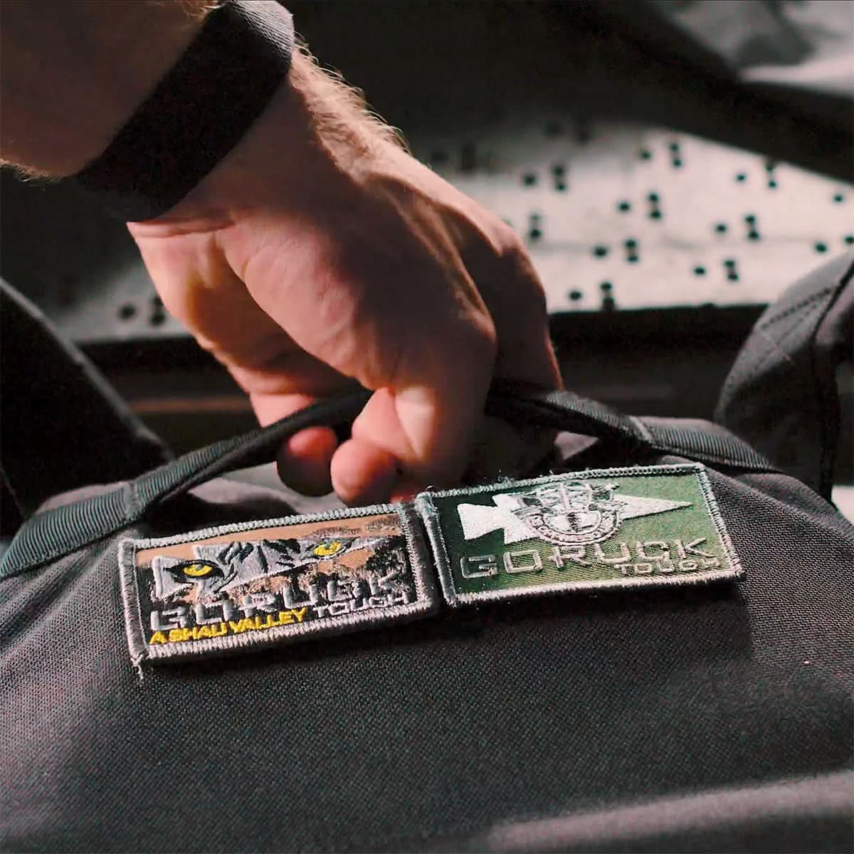 Hand gripping GORUCK backpack handle with GORUCK Tough gear patches attached