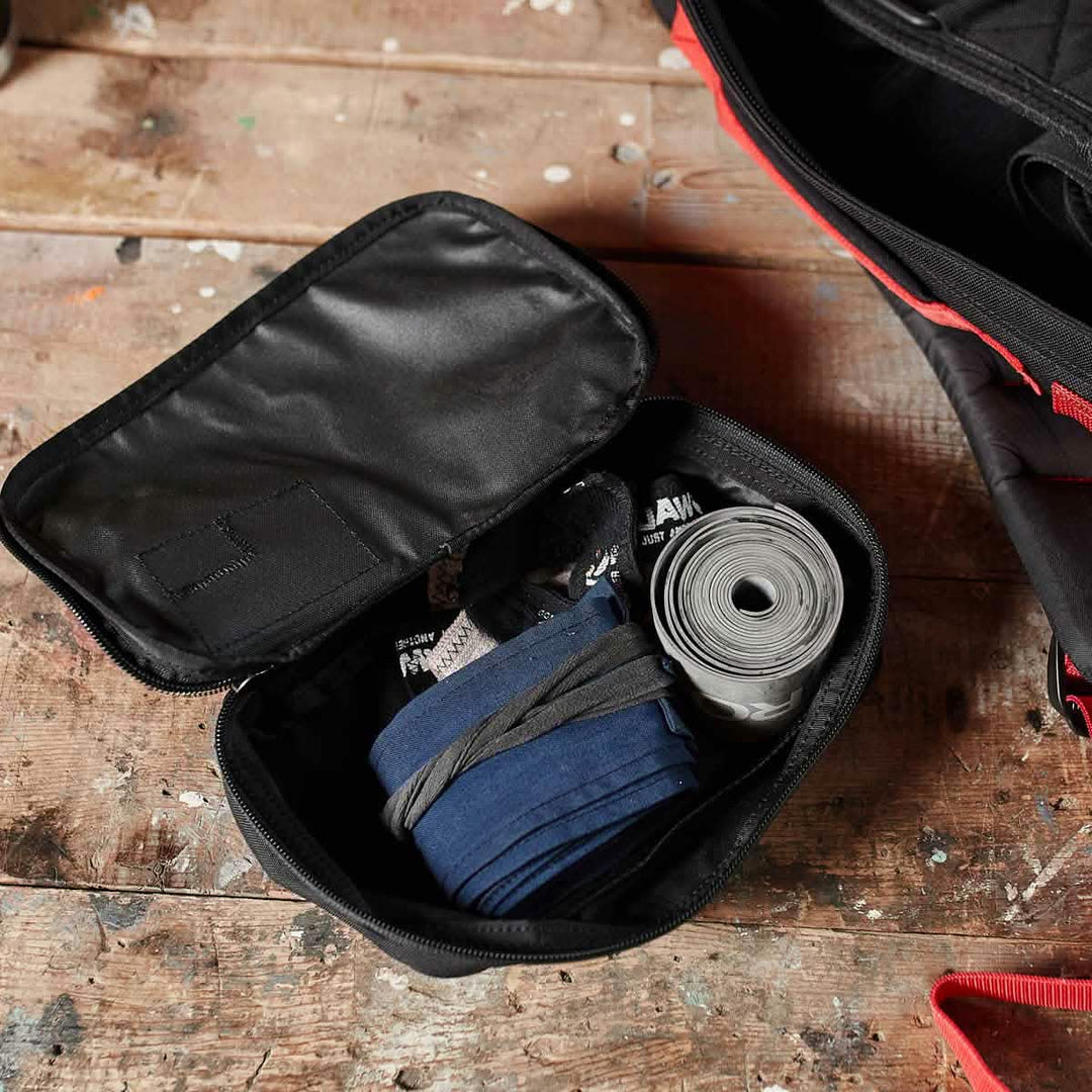 The GORUCK Shadow Pockets in black Cordura keep your hand wraps and tape organized on a worn wooden surface.