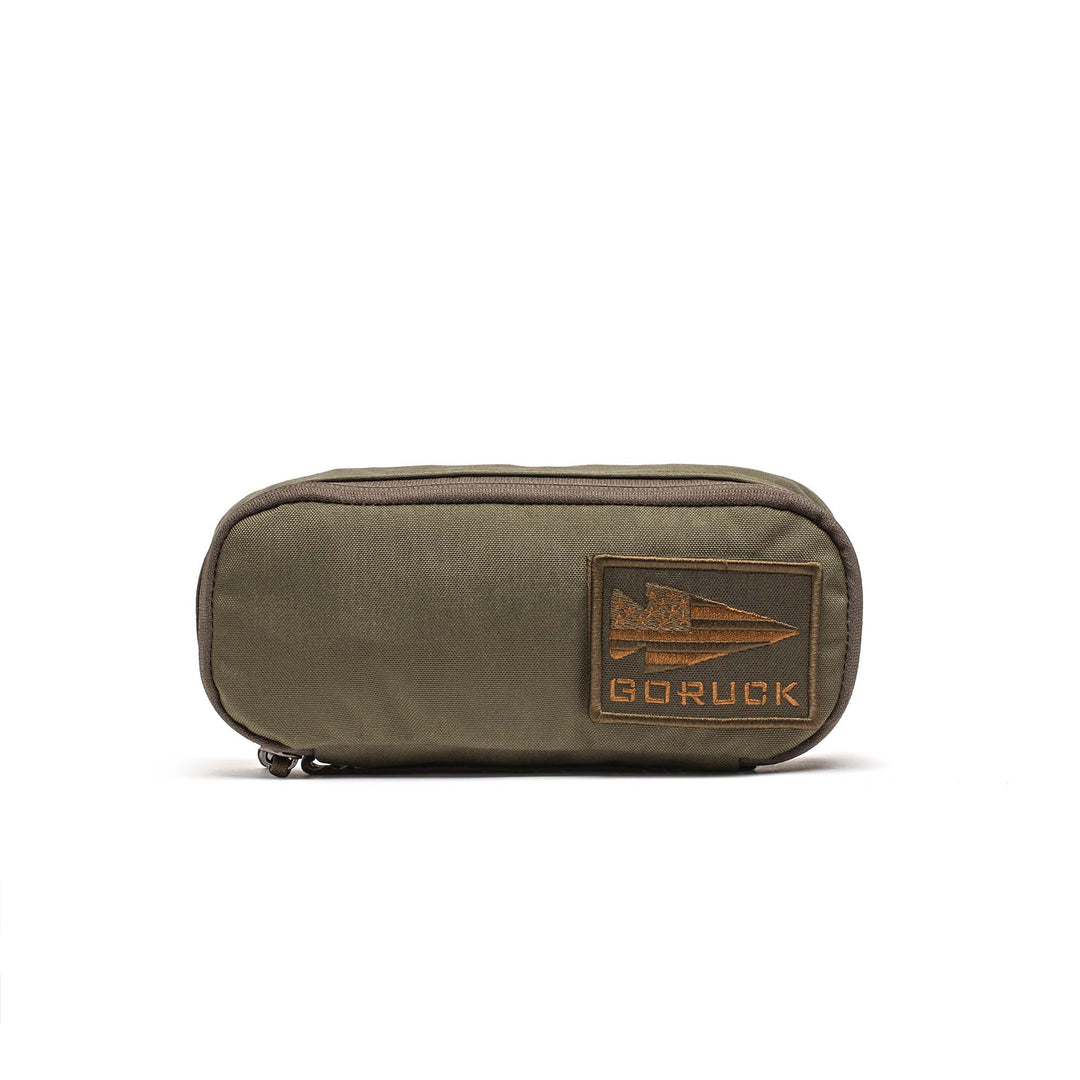 The GORUCK Shadow Pockets are olive green Cordura zippered organizers with a brown GORUCK patch on the front, ideal for keeping your rucksack neat and organized.