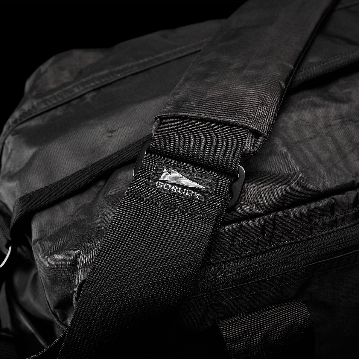 Close-up of a black bag with a strap and a metal buckle labeled 