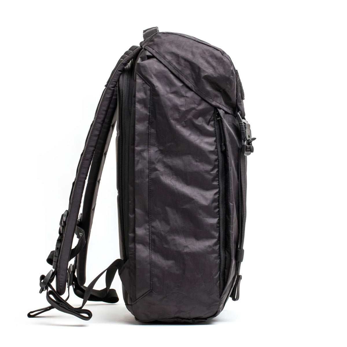 Black backpack standing upright on its side against a white background, showing its profile and straps.