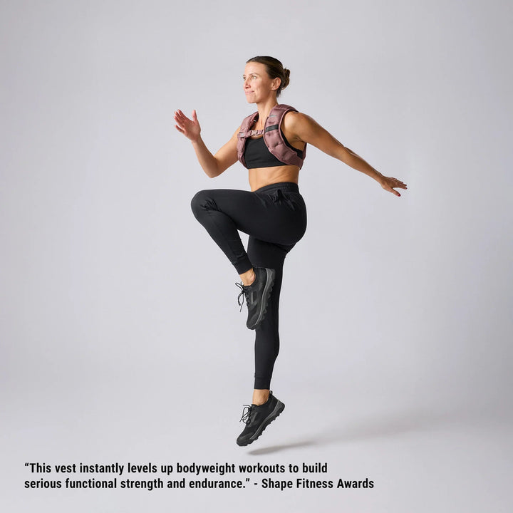 Woman doing high knee exercise in GORUCK weighted vest, athletic apparel, studio background