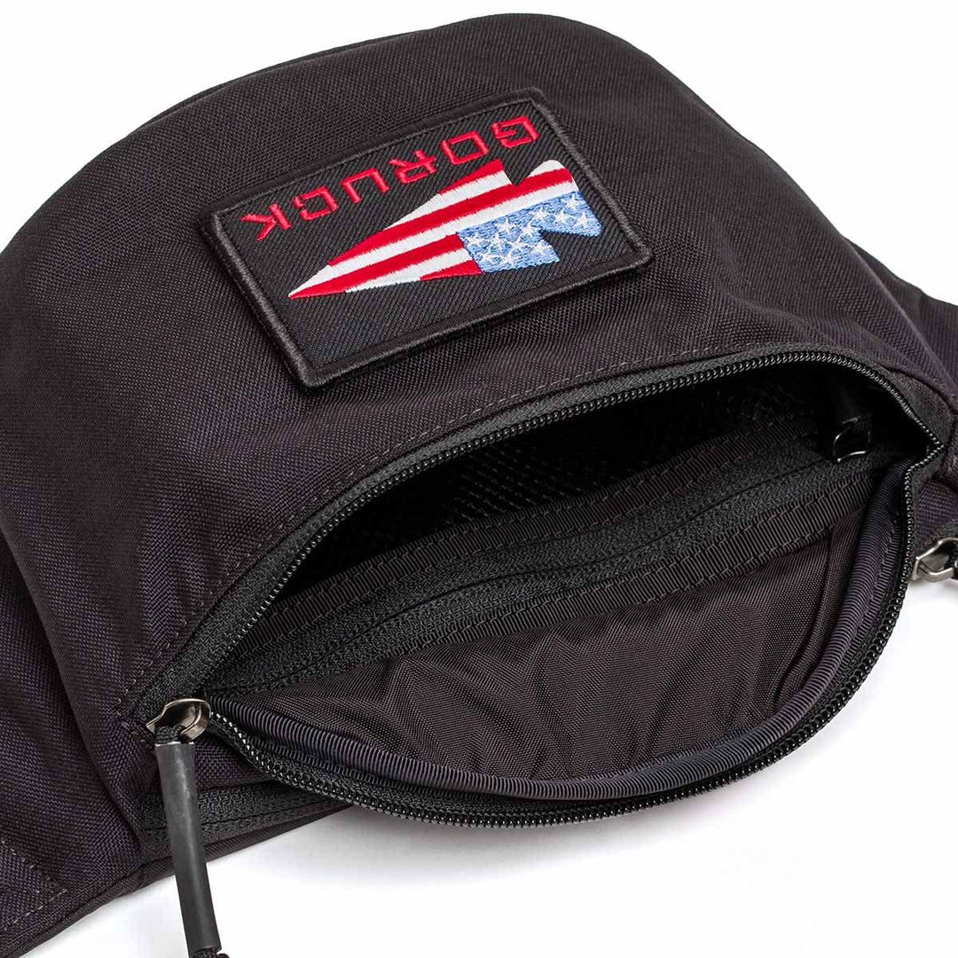GORUCK tactical black fanny pack with American flag patch and open zippered pocket