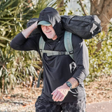 Man wearing black GORUCK ToughMesh hoodie rucking with weighted sandbag outdoors