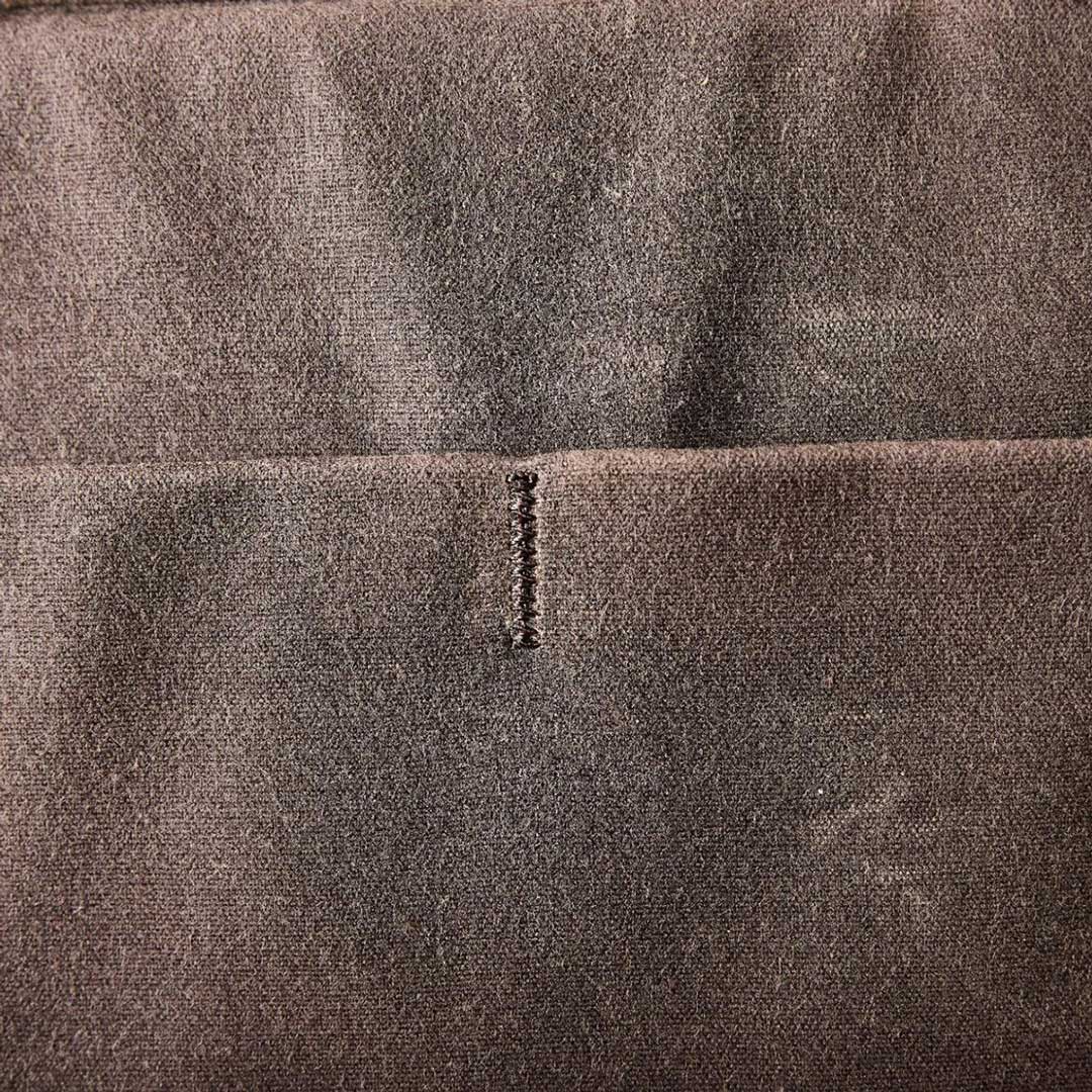 Close-up of a brown fabric with a horizontal seam and a small section of vertical stitching.