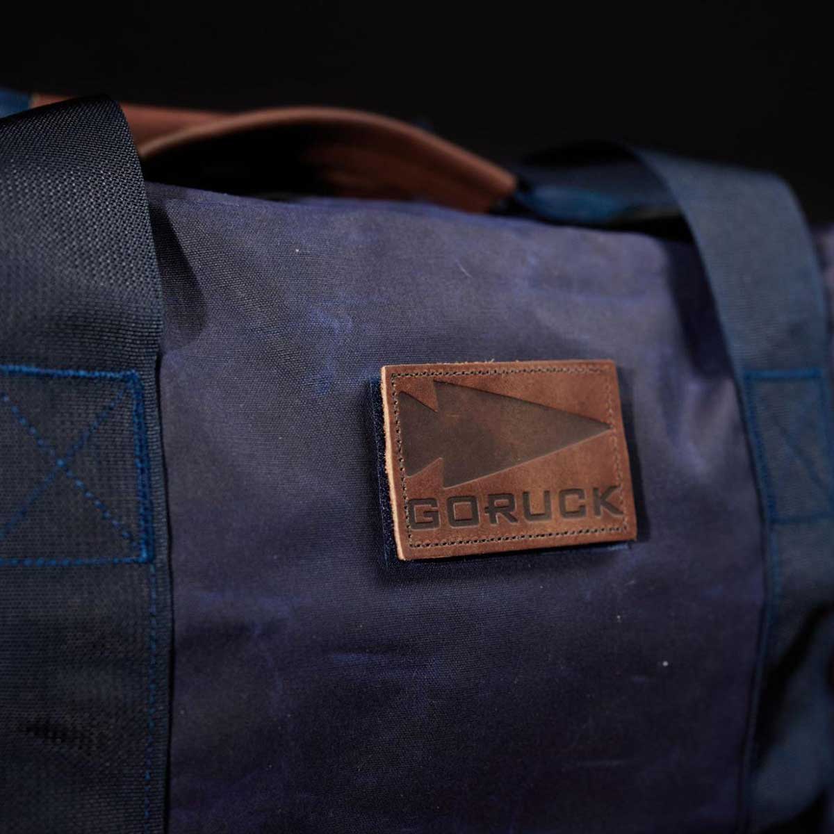 Close-up of a dark blue bag with a leather patch that reads 