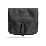 The Wire Dopp is a black CORDURA fabric pouch with a buckle closure and front Velcro patch, ideal for organizing your travel essentials. Shown on a white background.