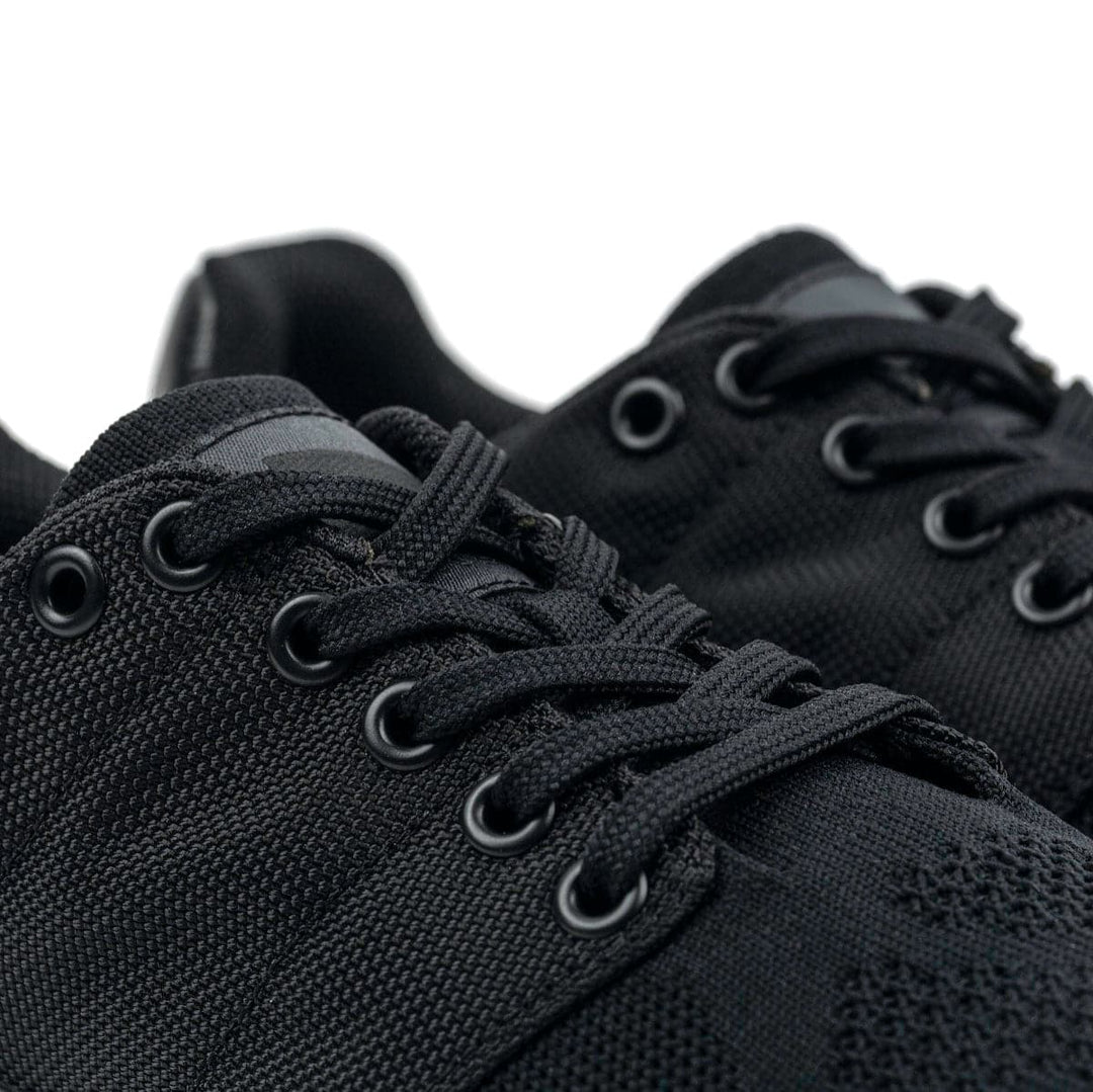 Close-up of the GORUCK Ballistic Trainers - Blackout + Black, showcasing black lace-up sneakers with 3X Support™, textured fabric, and metal eyelets; ideal for functional fitness.