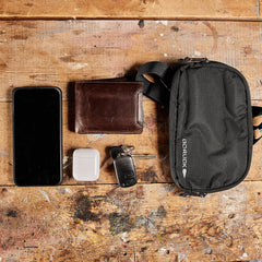 GORUCK belt bag on wooden table with phone, wallet, AirPods, and keys, everyday carry gear