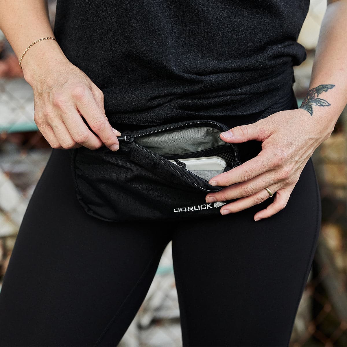 GORUCK belt bag unzipped, revealing inner pocket, worn by person in black activewear