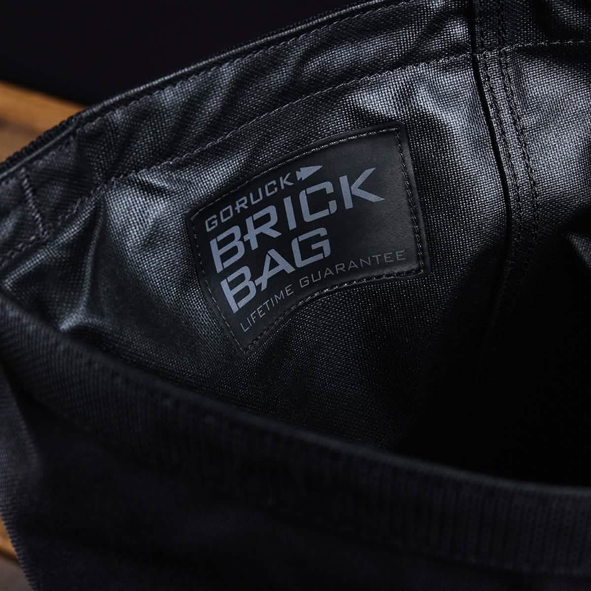 Close-up of a black fabric bag by GORUCK, called the Brick Bag (5-50 LBS), reminiscent of military gear, with a 