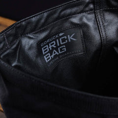 Close-up of a black fabric bag by GORUCK, called the Brick Bag (5-50 LBS), reminiscent of military gear, with a "LIFETIME GUARANTEE" label.