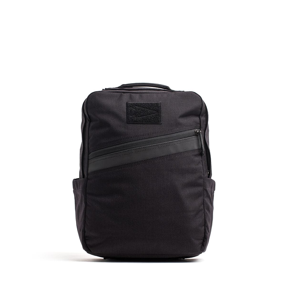 The GORUCK KR1, a sleek black school backpack, features a front diagonal zipper pocket and side pockets while standing upright, offering both style and durability.