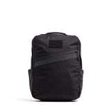 The GORUCK KR1, a sleek black school backpack, features a front diagonal zipper pocket and side pockets while standing upright, offering both style and durability.