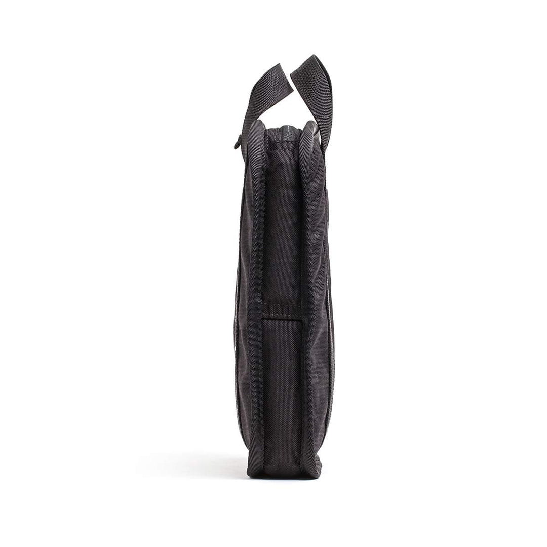 Side view of a GORUCK Sand Ruck Plates shoulder bag, made from black fabric with two handles, designed for rucking, standing upright against a white background.