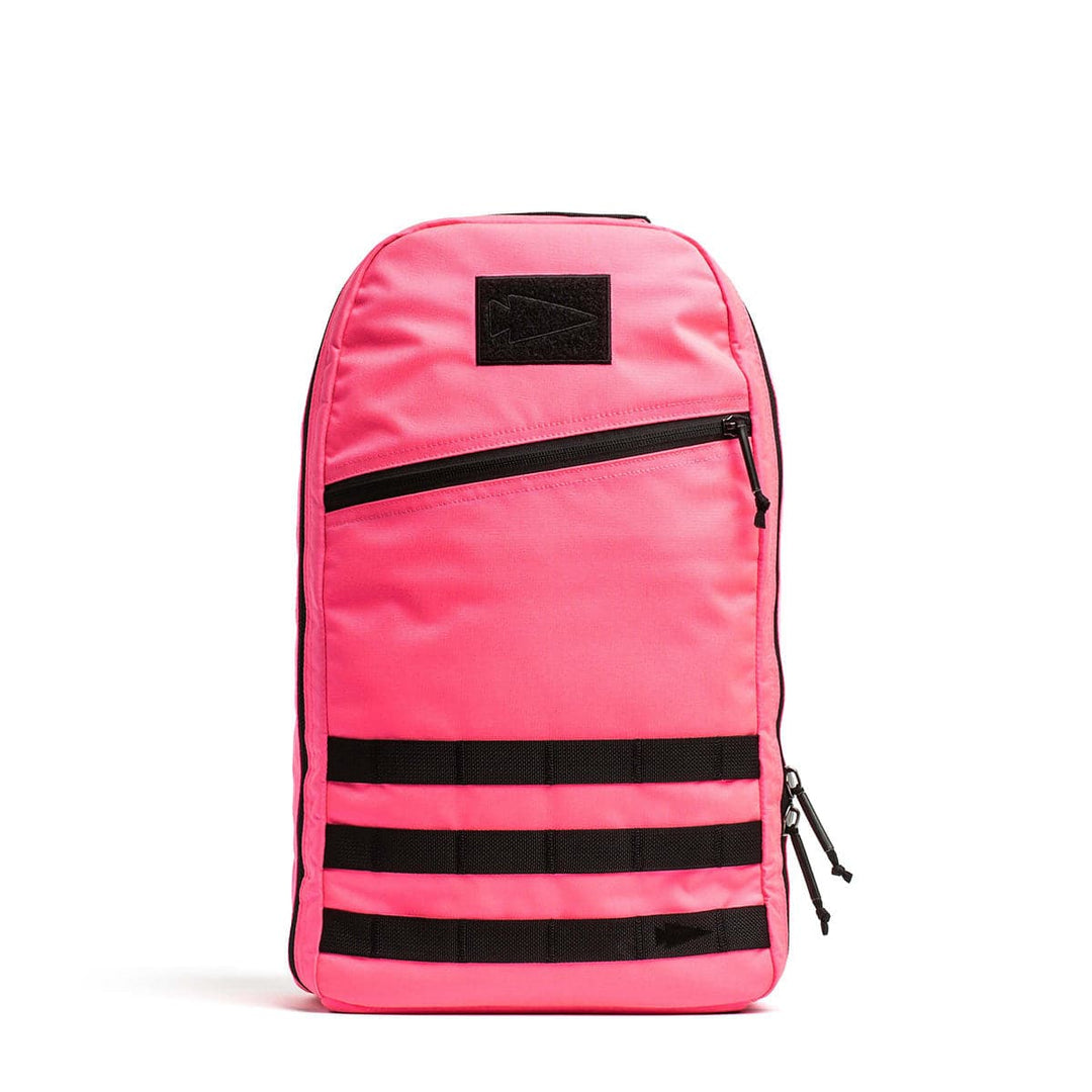 Bright pink 15L Bullet Ruck - Classic by GORUCK, featuring black zippers and horizontal black straps on the front.