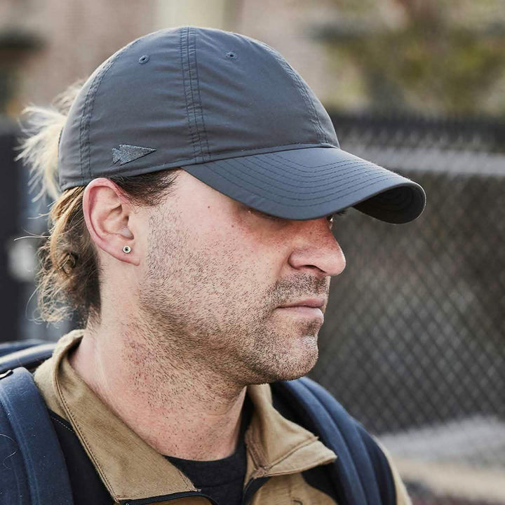 GORUCK man wearing charcoal cap outdoors with arrowhead logo, tough rucking gear
