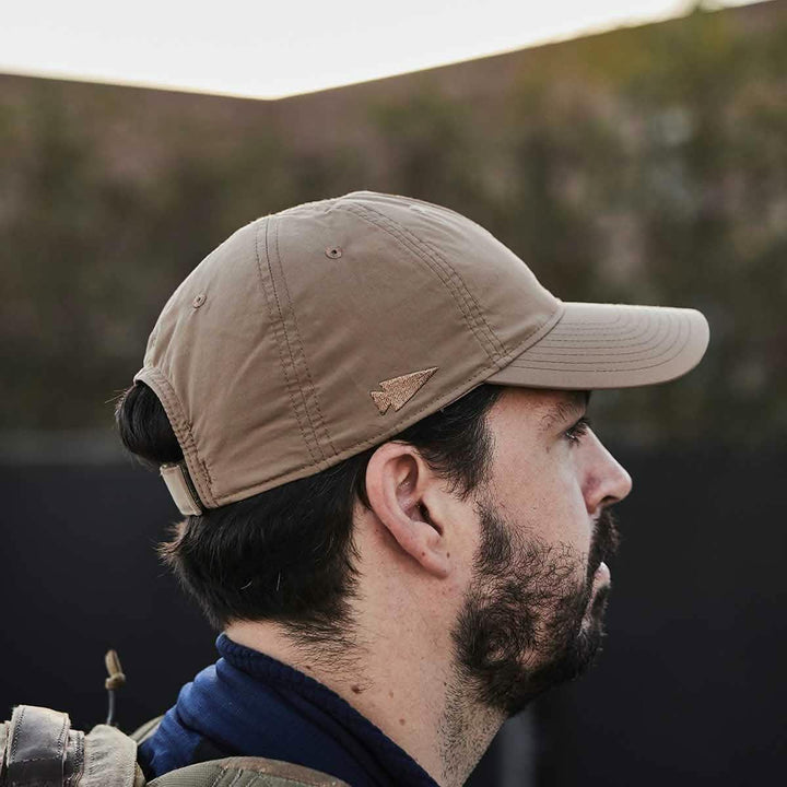 Man wearing tan GORUCK cap outdoors, side profile, rugged rucking gear style