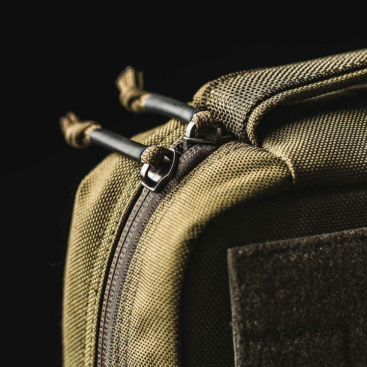 Close-up of the GORUCK GR2 Field Pocket, a khaki Cordura pouch with zipper and pull cords, displayed against a black background.