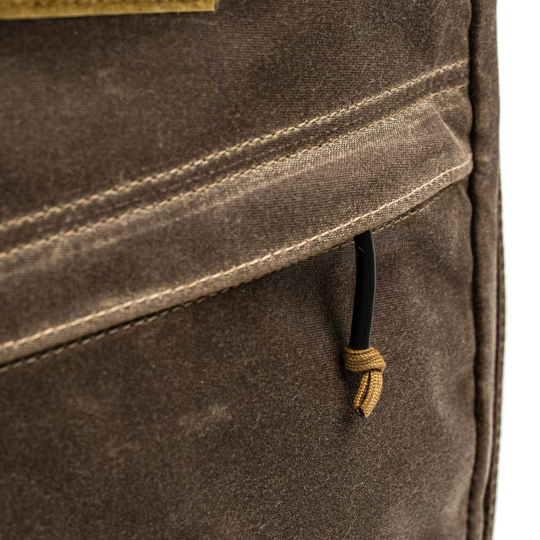Close-up of the GR1 USA - Heritage by GORUCK, a brown fabric bag crafted from durable waxed duck canvas, featuring a pocket and a knotted pull string on the zipper.