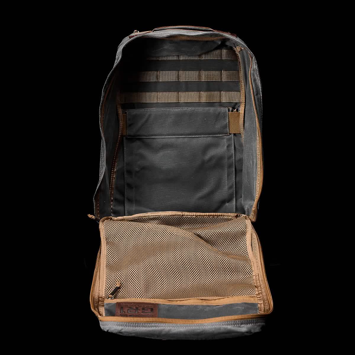 Open gray and tan GORUCK GR1 USA - Heritage Backpack displayed on black background, featuring its mesh pocket and interior compartments, crafted from durable waxed duck canvas.