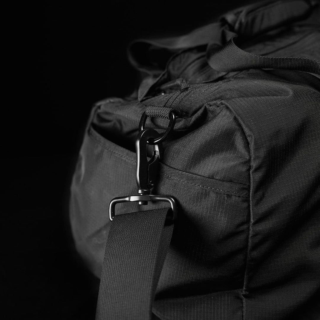 Close-up of the GORUCK Gym Bag - Ripstop ROBIC®, a sleek black bag crafted from durable ripstop nylon, featuring a metal clasp on its shoulder strap.