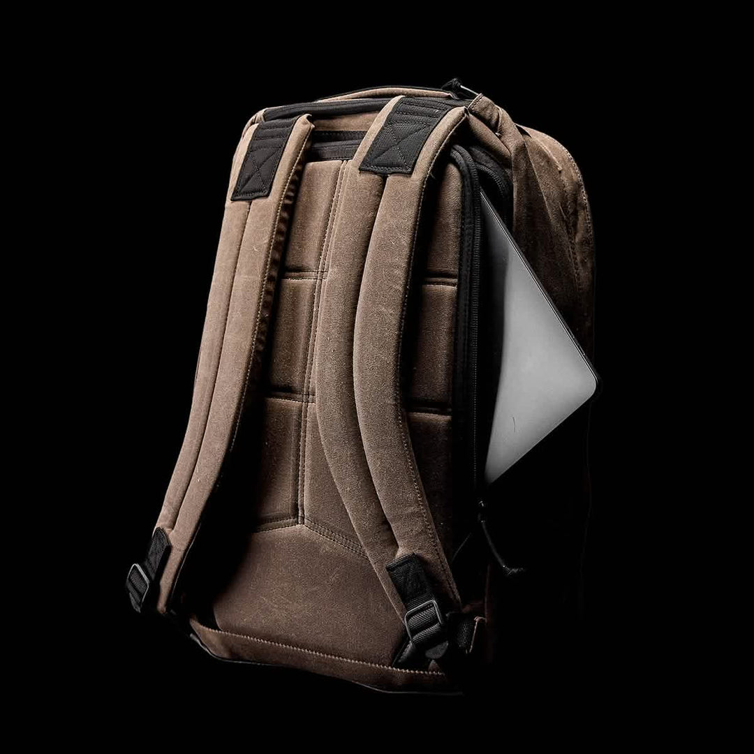 The GORUCK GR1 USA - Heritage is a retro brown canvas rucksack with black straps and a durable laptop compartment, partially visible against the black background.