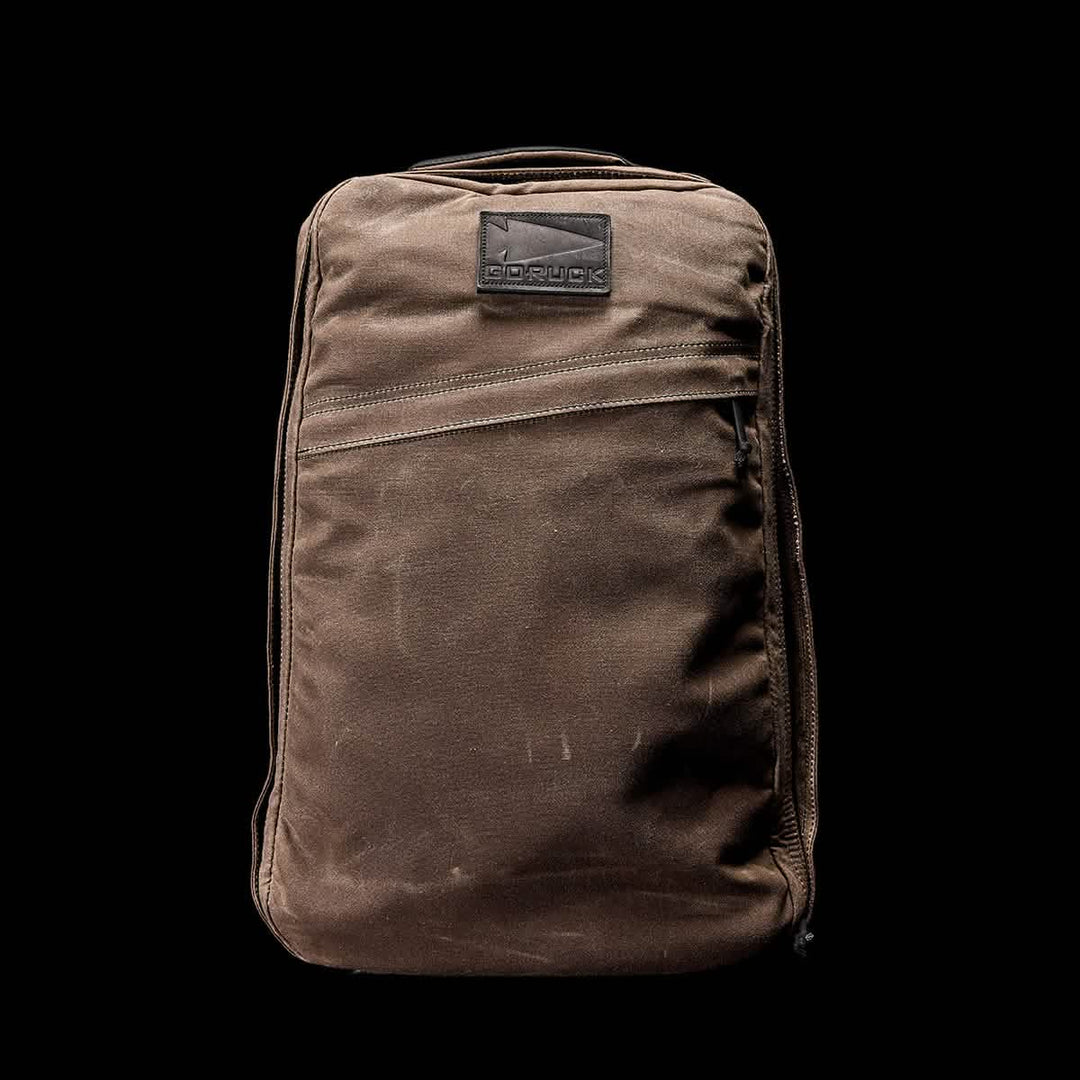The GR1 USA - Heritage by GORUCK is a brown retro canvas rucksack on a black background, featuring a front pocket and logo patch, crafted from durable waxed duck canvas for a timeless look.