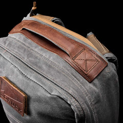 Close-up of a gray GR1 USA - Heritage rucksack by GORUCK, featuring brown leather accents on the handle and trim, crafted from durable Waxed Duck Canvas with a classic Martexin Wax Finish.