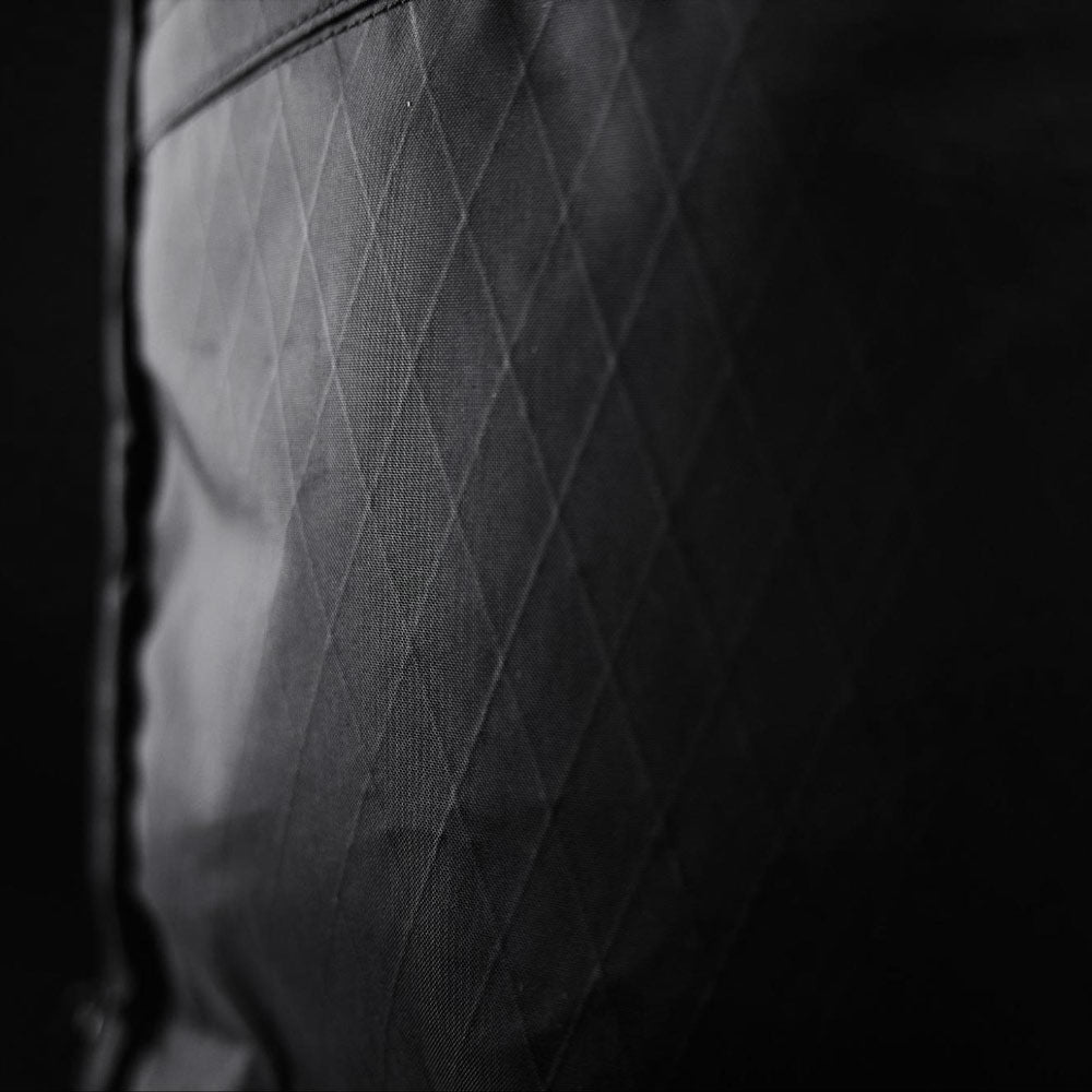 Close-up of black fabric with a diamond pattern texture, showing light reflection and stitched lines.