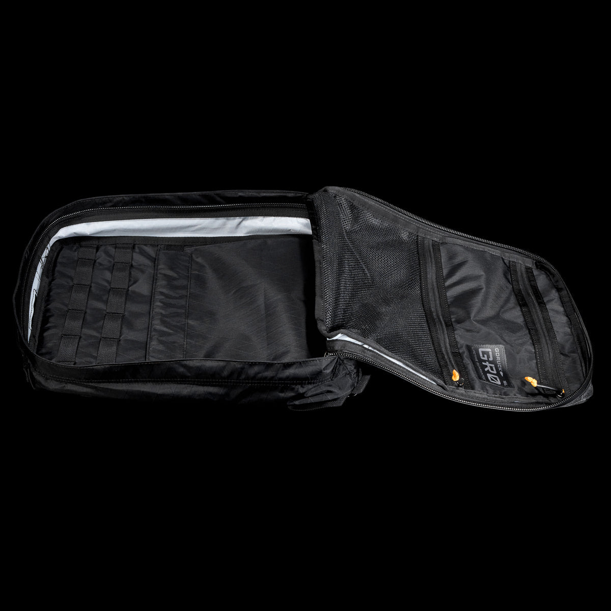 Open black backpack with organized compartments and zippered mesh pockets visible against a black background.