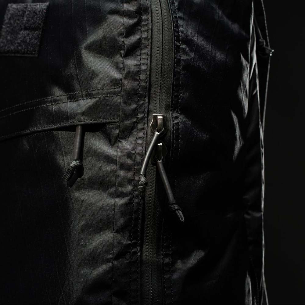 Close-up of a black backpack zipper with two pulls against a dark background.