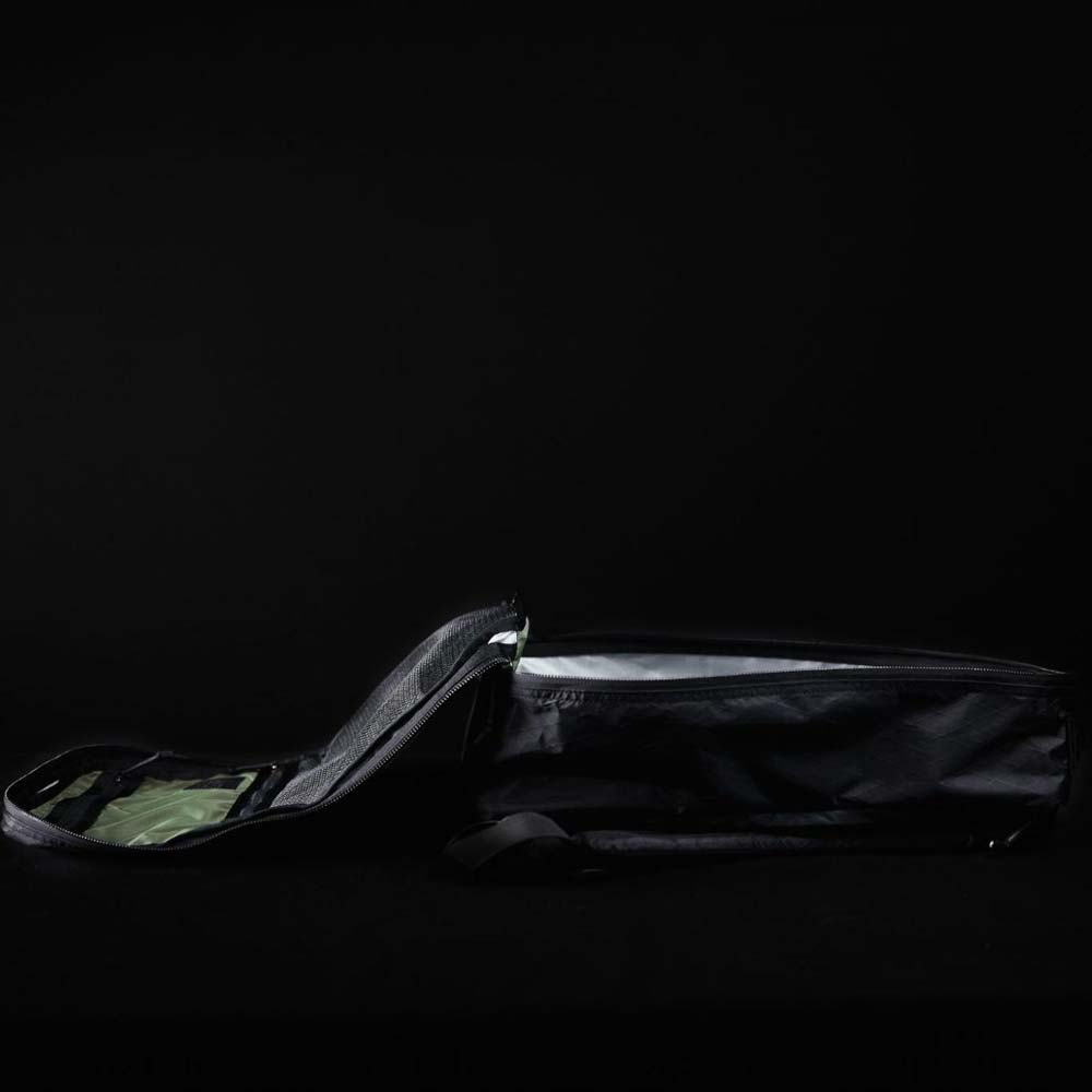 A black duffel bag lies open on a dark surface against a black background.