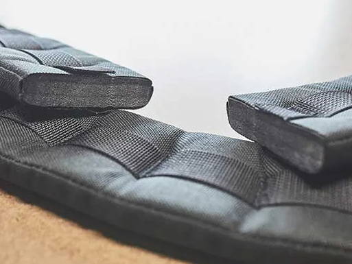 Close-up of weighted fabric straps with stitched pockets, lying on a flat surface.