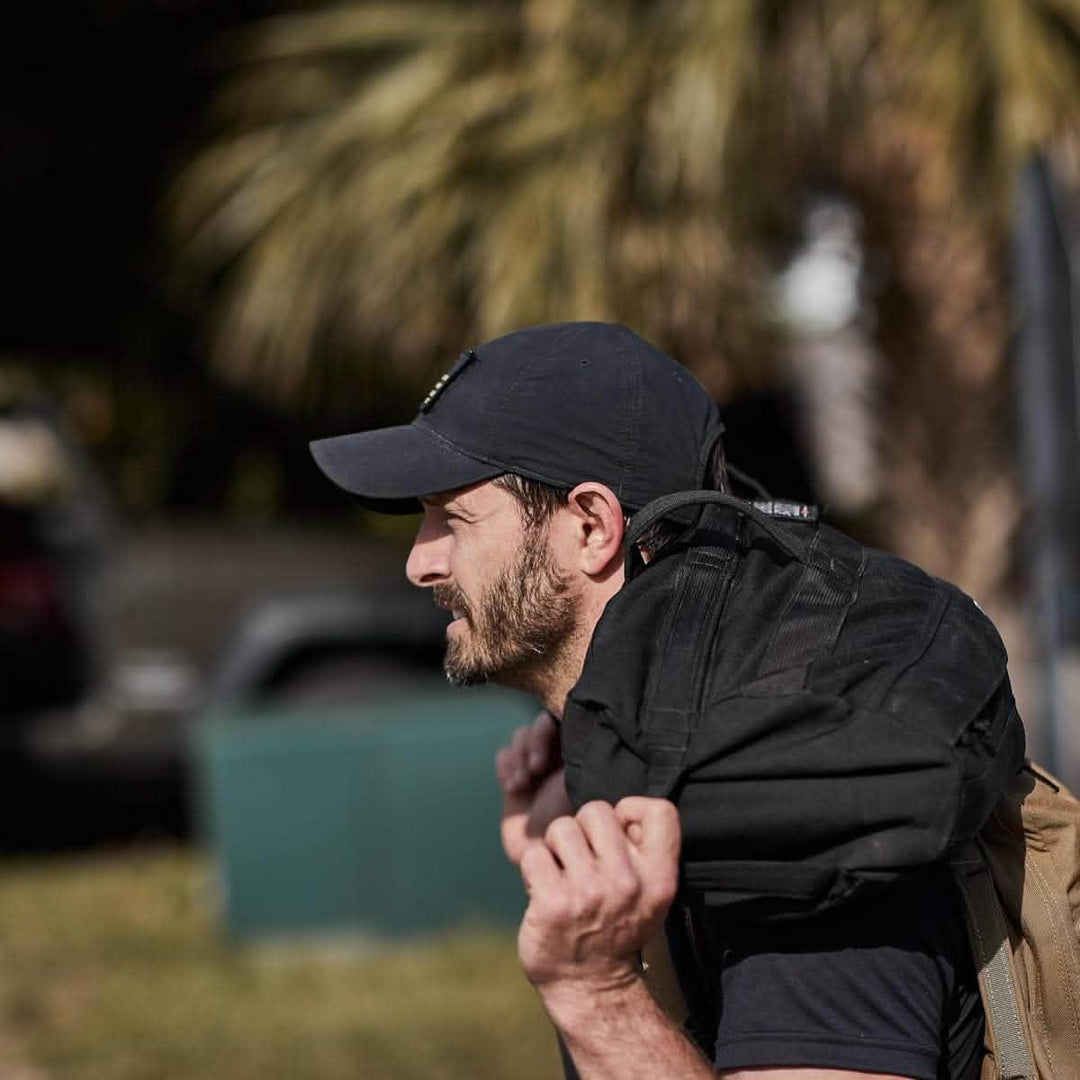 Man rucking outdoors wearing GORUCK tac hat and carrying a black weighted backpack