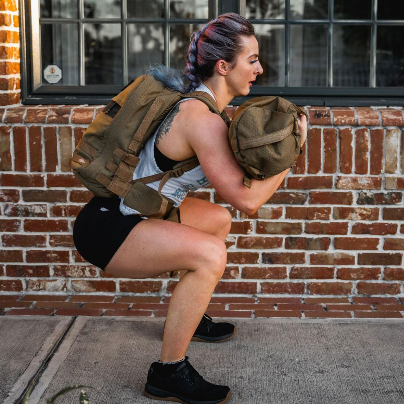 A woman squatting with a backpack.