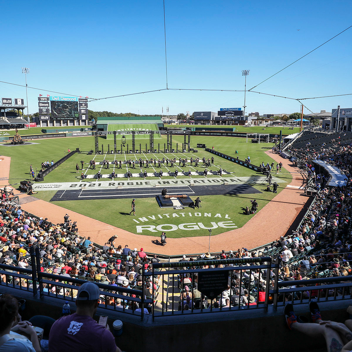 A large crowd watches athletes compete at the 2021 Rogue Invitational in an outdoor stadium.