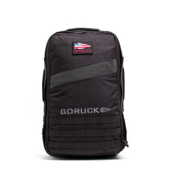 The Rucker 5.0 is a black GORUCK rucksack with a patch and MOLLE webbing on the front, designed for rucking and carrying ruck plates, shown against a white background.