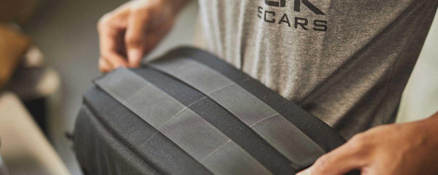 Close-up of a person holding a black bag while wearing a grey t-shirt with text on it.