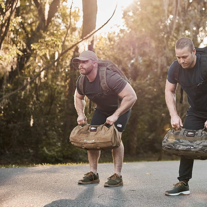 Two men outdoors performing rucking workout with GORUCK gear and rucksacks on a sunlit path