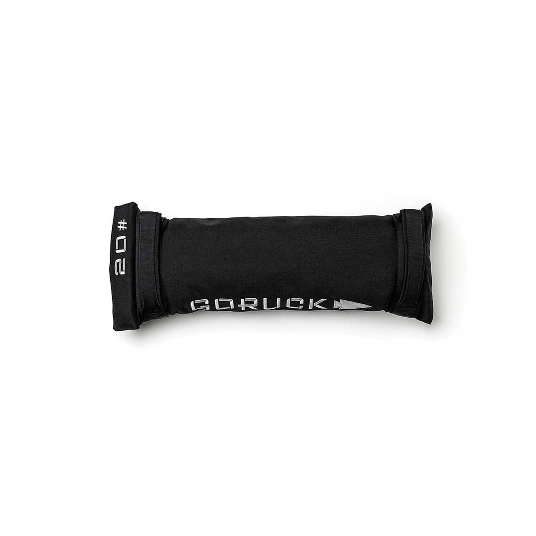 A black Simple Training Sandbag by GORUCK, featuring "20#" printed on it and equipped with heavy-duty handles, lies on a white background—ideal for your home gym setup.