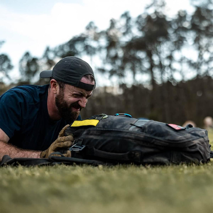 Man outdoors wearing cap, using GORUCK rucksack during rucking fitness training